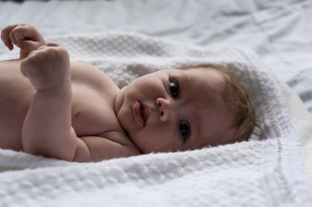 Little month old girl on a white sheet. Filmed in daylight.