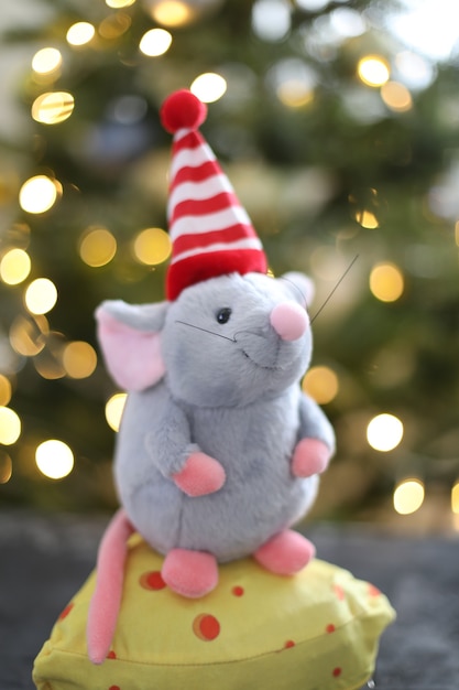 Little mouse toy and new year decorations by bokeh lights of a Christmas tree