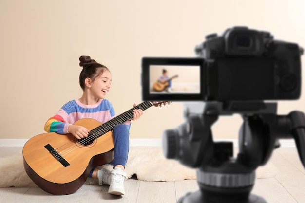 Little music teacher recording guitar lesson indoors