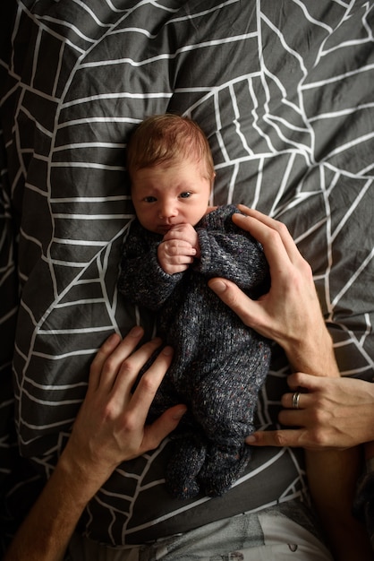 little newborn boy in the eighth month, lies in the hands of caring parents.