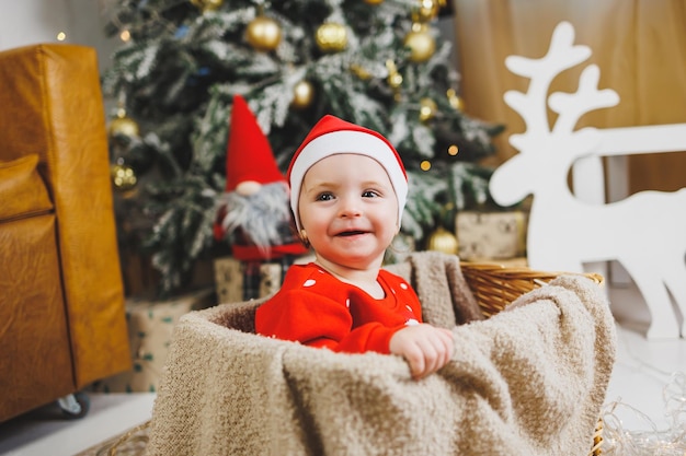 little oneyearold boy near the Christmas tree an idea for a children's photo for the new year studio New Year decoration Christmas gifts red children's festive costume