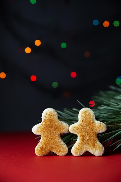 Little people made of toasted bread branch of new year tree closeup on redblack background with mult...