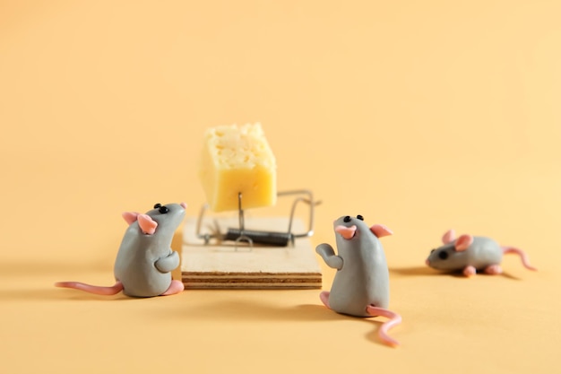 Little plasticine gray mice look at a piece of cheese in a mousetrap