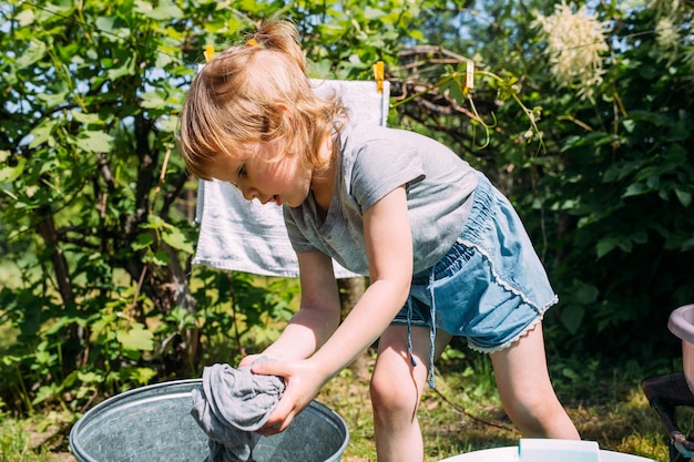 Little preschool girl helps with laundry child washes clothes in garden