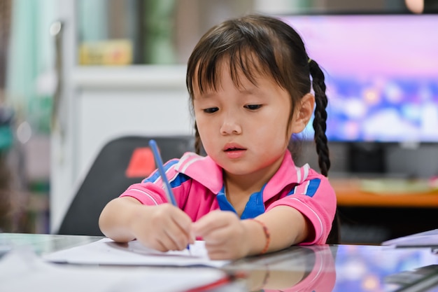 Little preschool girl making homework at home with serious face and unhappy