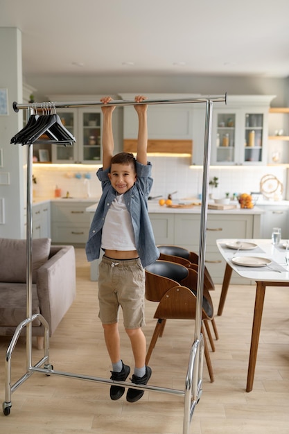 Little preteen boy child hanging on clothes hanger