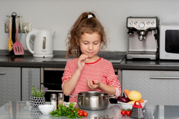 A little pretty girl cooks in the kitchen from fresh vegetables Conceptual photography