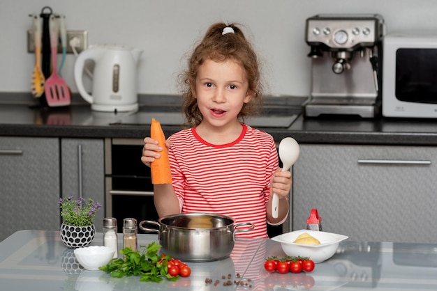 A little pretty girl eats carrots in the kitchen Conceptual photography Proper nutrition Diet