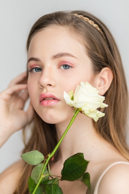 Little pretty girl in pink holds the bouquet of roses. Close up the flowers and face, little ballerina with a bouquet