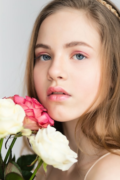 Little pretty girl in pink holds the bouquet of roses. Close up the flowers and face