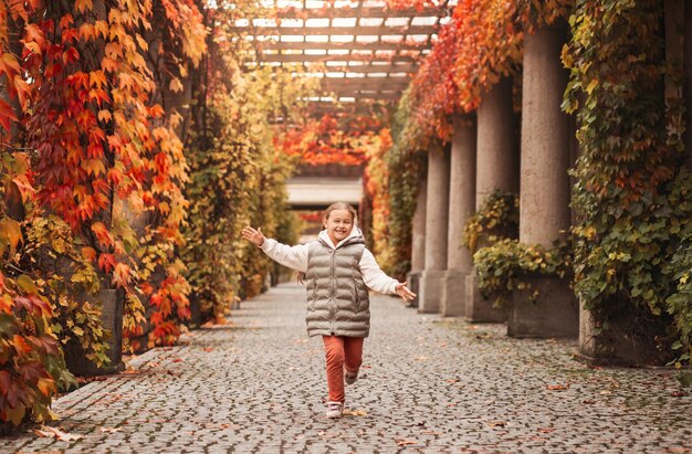 A little pretty girl runs through a beautiful autumn park