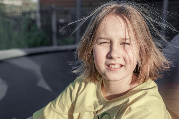 Little pretty smiling girl sitting on the trampoline