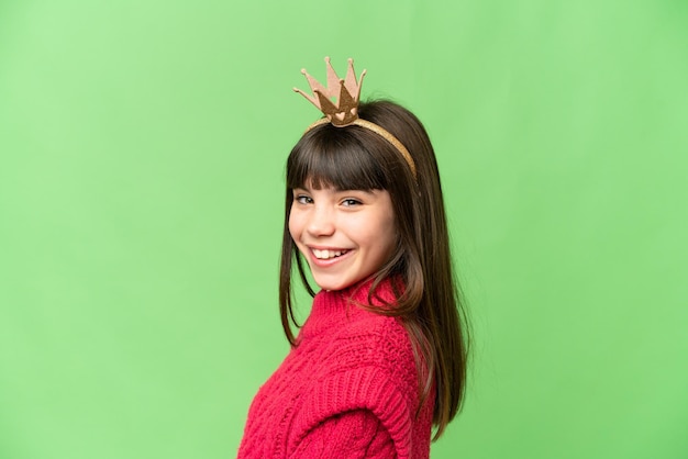 Little princess with crown over isolated chroma key background smiling a lot