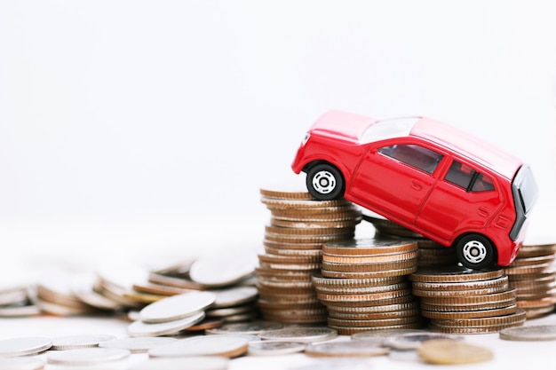 Little red car over a lot of money stacked coins. for  bank loans costs finance. insurance, buying car finance concept. buy and pay by installments down payment a car.