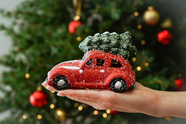 Little red machine in a female hand on the of the Christmas tree.