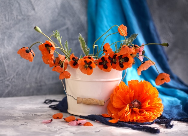 A little red poppies bouquet in white vase