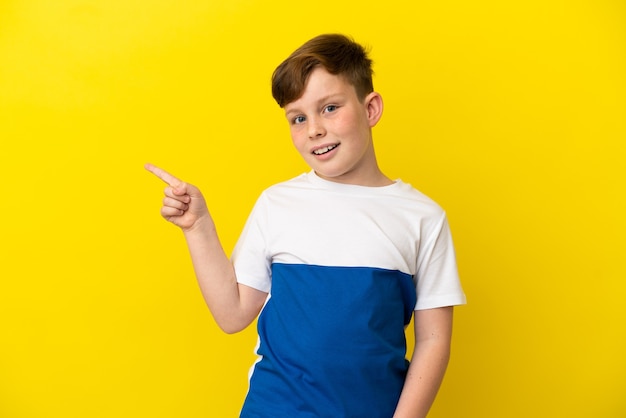 Little redhead boy isolated on yellow background intending to realizes the solution while lifting a finger up