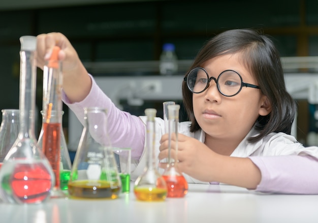 Little scientist in lab coat making experiment 