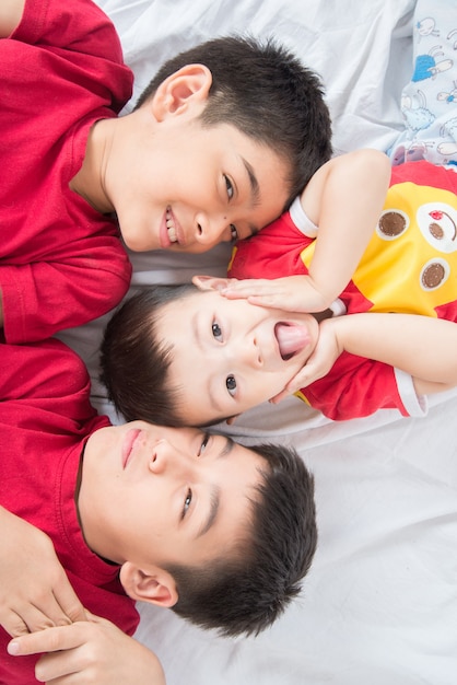 Little sibling boy lay down on the floor look at camera love ly and happy