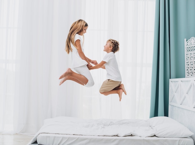 Little siblings jumping in bed together