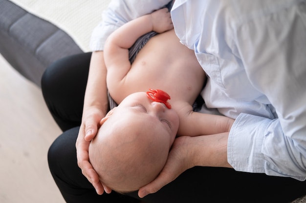 Little sleeping baby boys face in mother hands. motherhood concept.