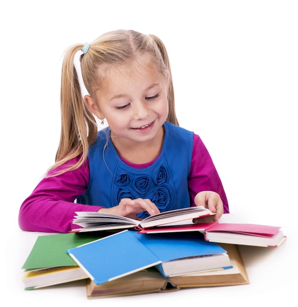 Little smart girl holding a book and reading it on a white background