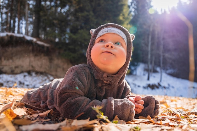 Little smiling baby boy playing in yellow foliage Autumn in the city park