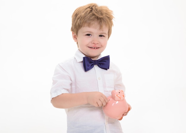 Little smiling boy holds piggy bank. Boy holding moneybox. Saving money concept. Piggy bank. Finance. Bank advertising. Safety money concept. Small boy in white shirt. Close Up portrait.