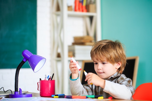 Little smiling boy learns to paint at school.