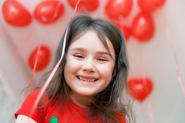 little smiling girl close up portrait with red balloons on a background