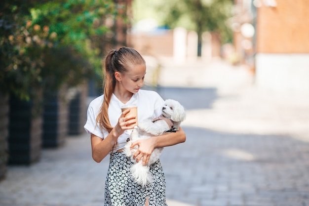 Little smiling girl playing and hugging puppy in the park