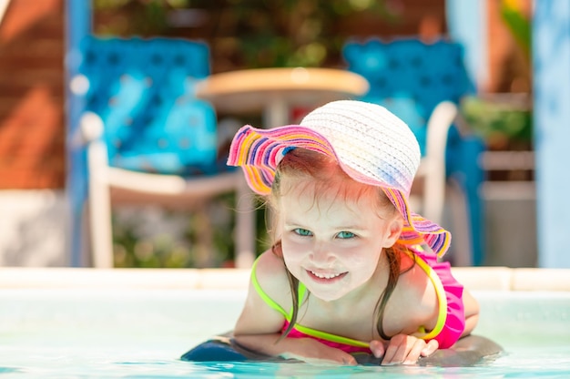 Little smiling pleasured blond girl lying in front of the water on the sunshine pool