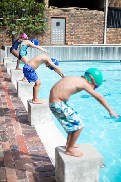 Little swimmers taking position to jump in swimming pool