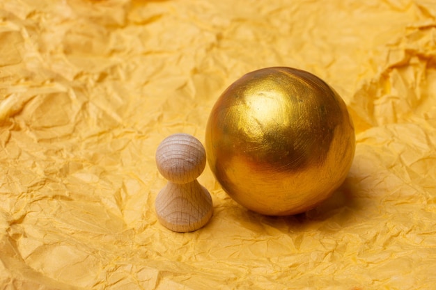 Little tiny wooden person figurine and gold color ball