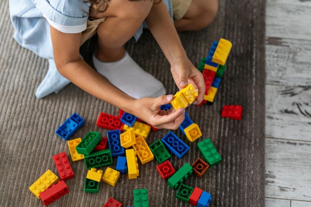 Little toddler boy playing with colorful plastic blocks at home building creative game imagination