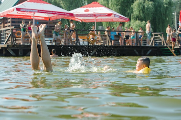 Little toddler kid swimming in lake with inflatable arms aids support