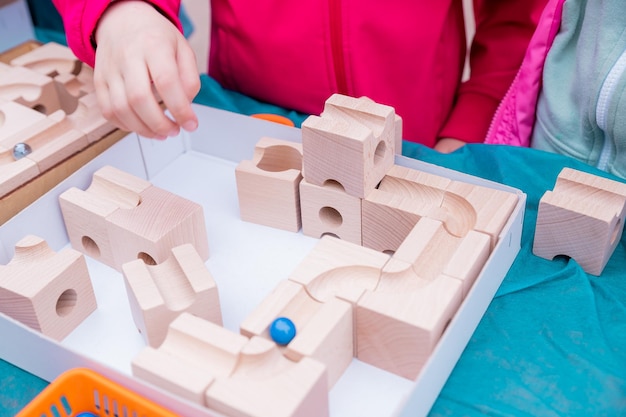 Little toddler plays with a wooden constructor preschool child learning at home to make mosaic Early development Playing and learningChildren hands collect constructor cubes activity concept