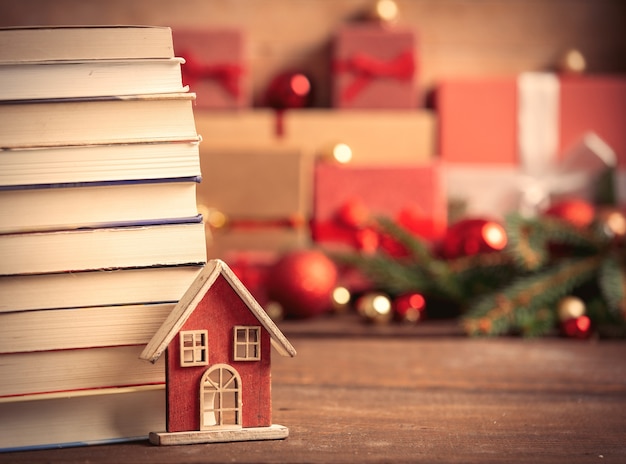 Little toy house with books and Christmas gifts on wooden table