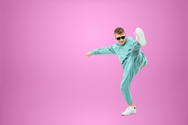 Little in a turquoise suit posing and fooling around on a pink, looking at the camera