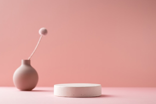 Little vase with dried flower and beton podium on a neutral pink background in shadows. Minimalist composition background, copy space side view