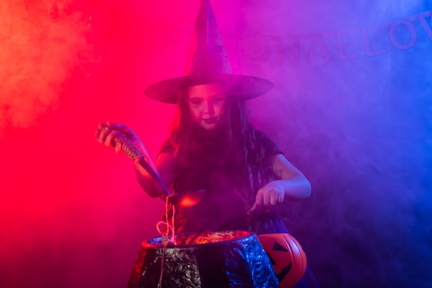 Little witch child cooking potion in the cauldron on halloween