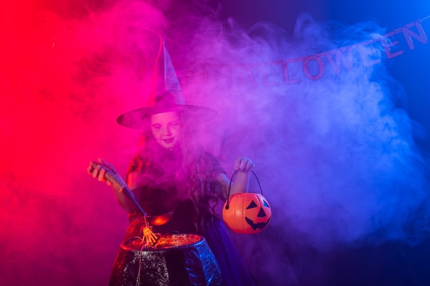 Little witch child cooking potion in the cauldron on halloween