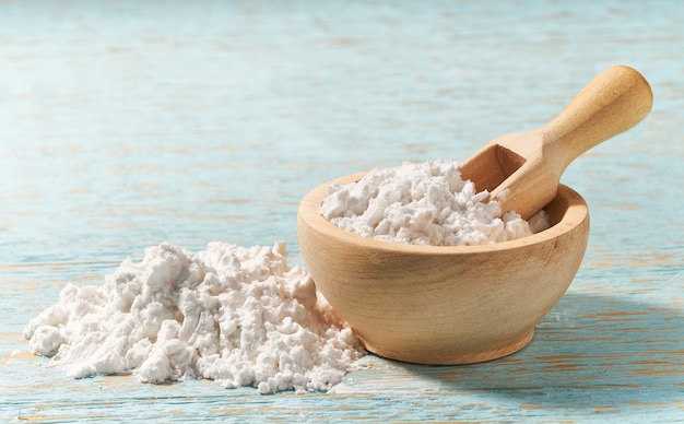 Little wooden bowl with corn starch on a wooden table, with copy space.