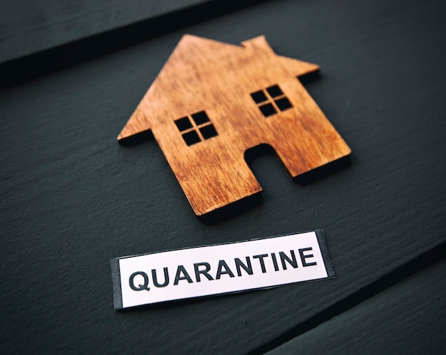 The little wooden house and banner with text "quarantine" on the table. Concept of coronavirus quarantine