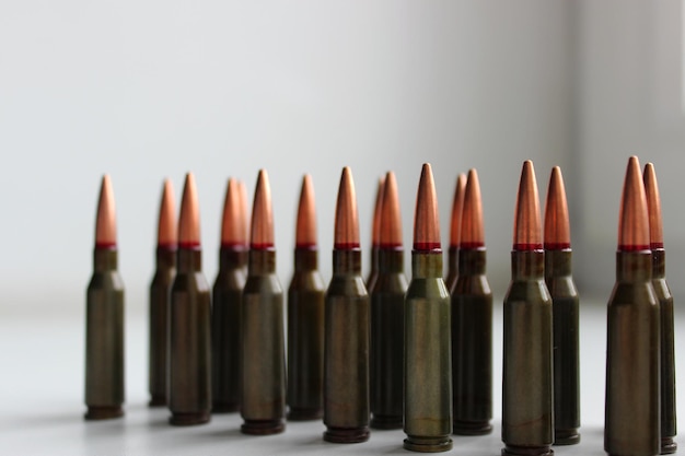 Live ammunition for assault rifle with red mark on a bullets in a row on white surface