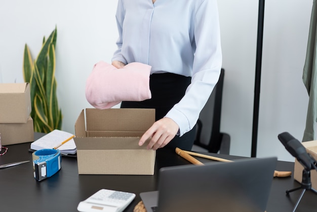 Live shopping concept a female dealer packing products into boxes after receiving orders from customers.