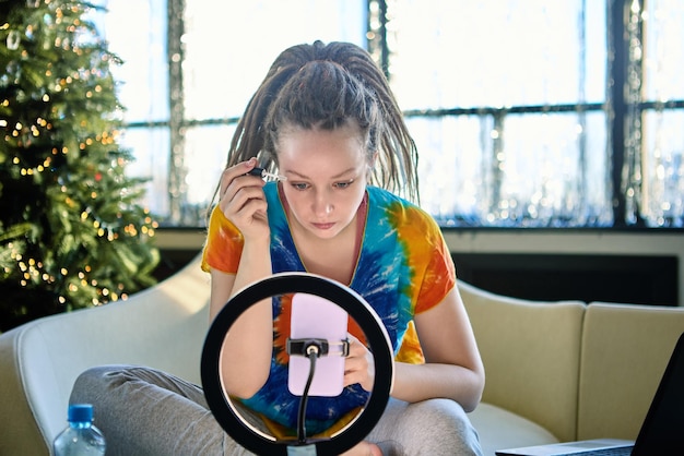 Live streaming by woman indoors with help of ring light and handy