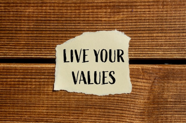 Photo live your values message written on ripped torn paper with wooden background conceptual live your values symbol copy space