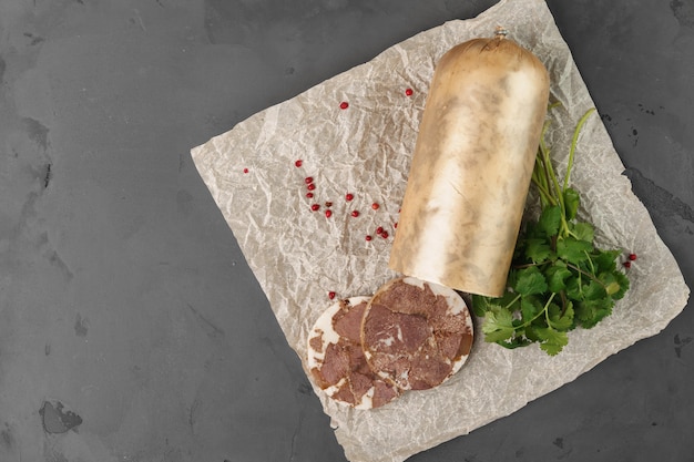 Liver sausage on parchment with parsley on gray background