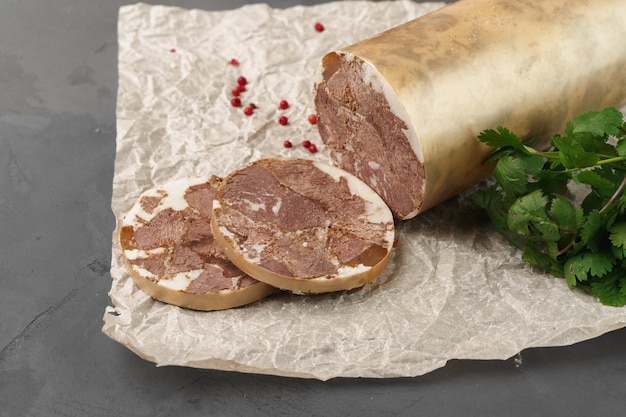 Liver sausage on parchment with parsley on gray close up